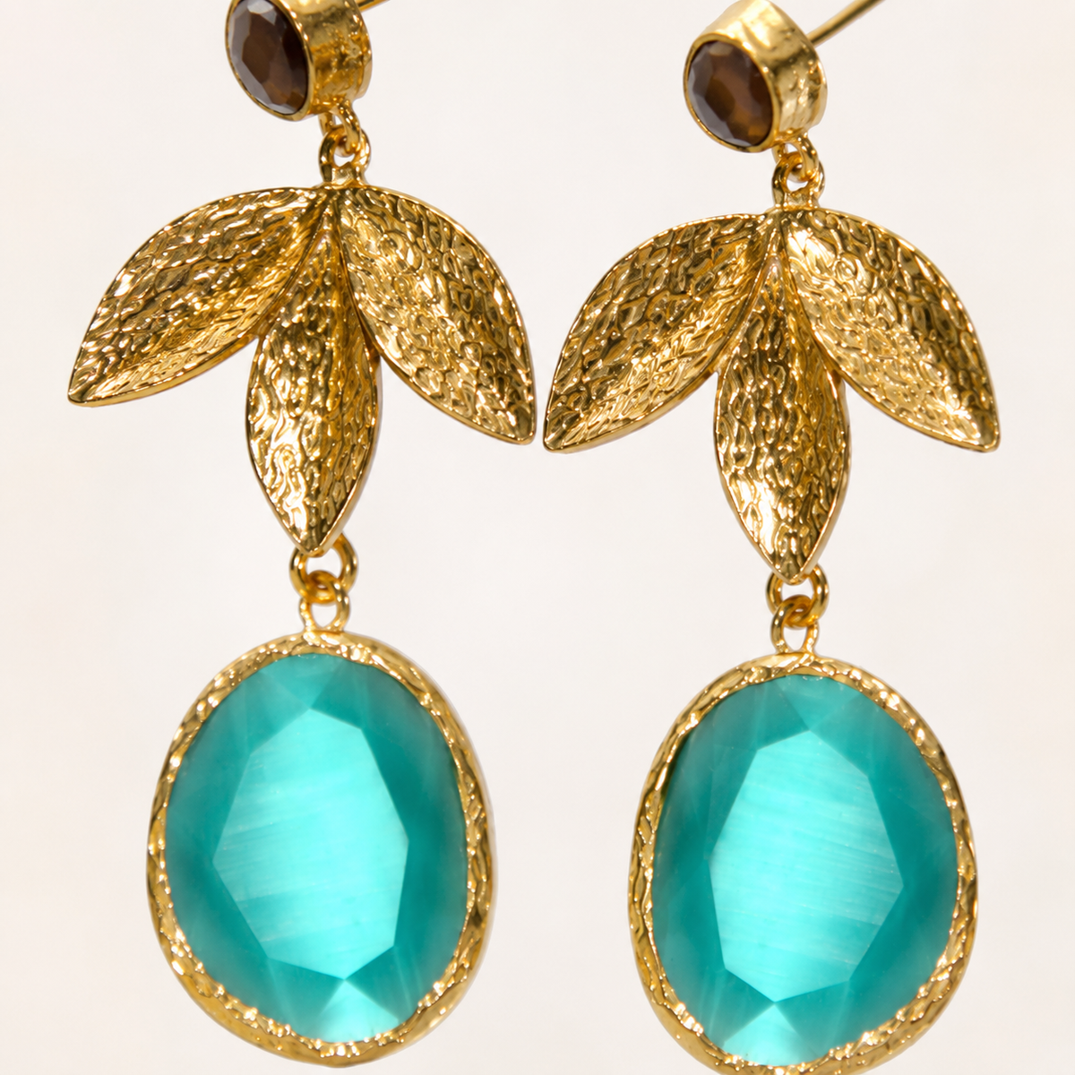 Close view of textured gold leaf details and turquoise stone drops.