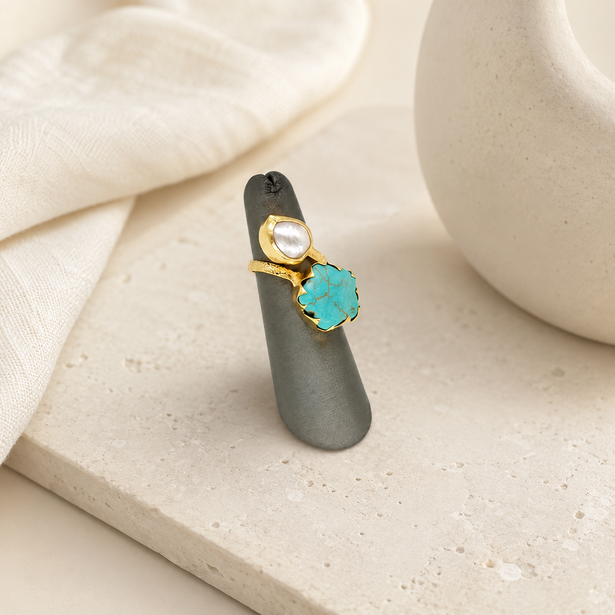 Gold-plated ring with a turquoise stone and pearl-like accent on a white background.