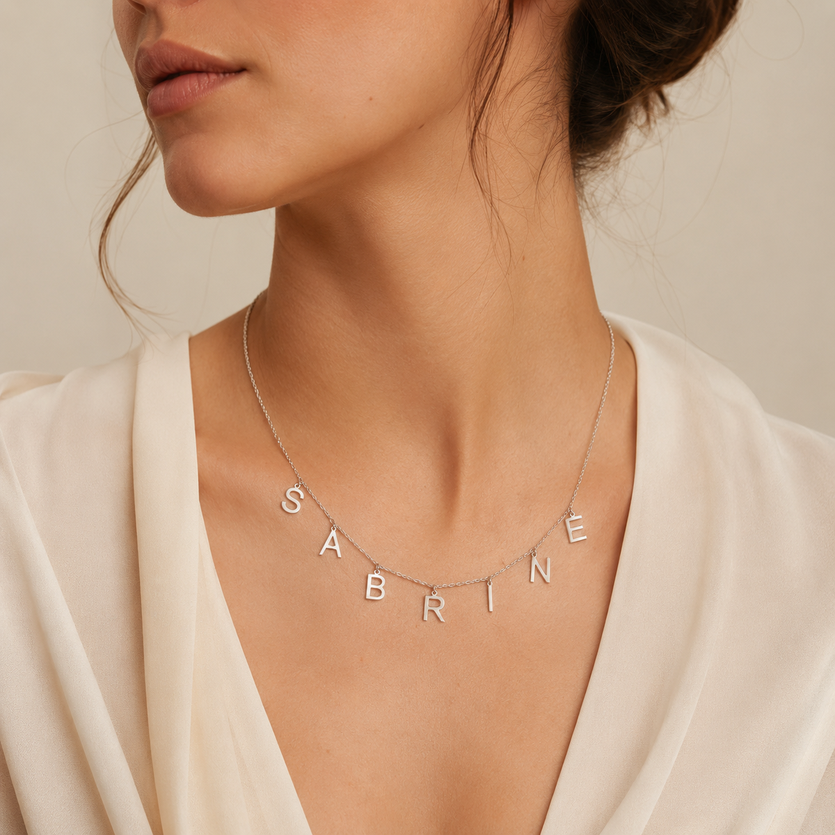 Custom initial necklace with spaced letter charms in a polished silver-tone look.