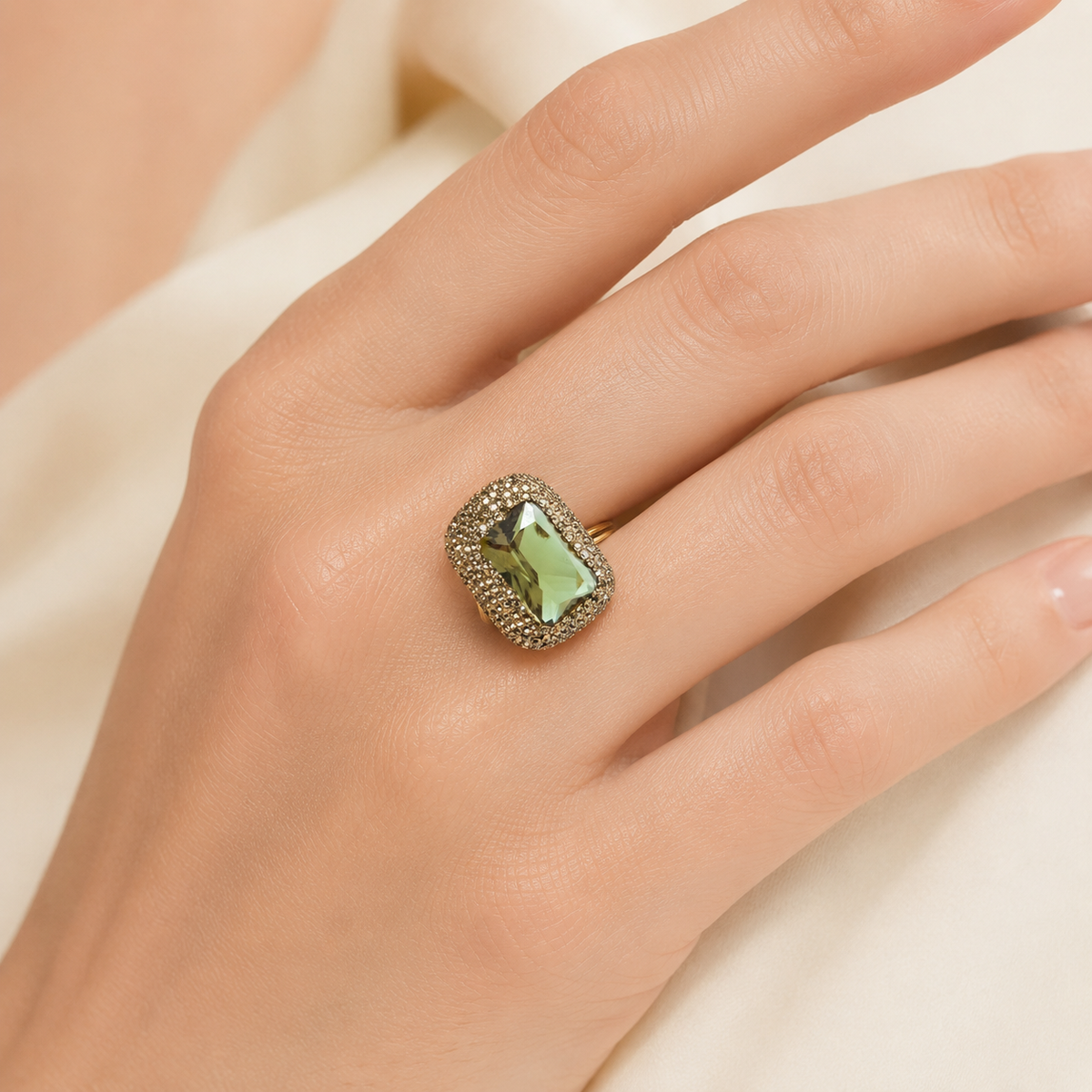 A gold-tone ring with a large faceted green stone and detailed frame.