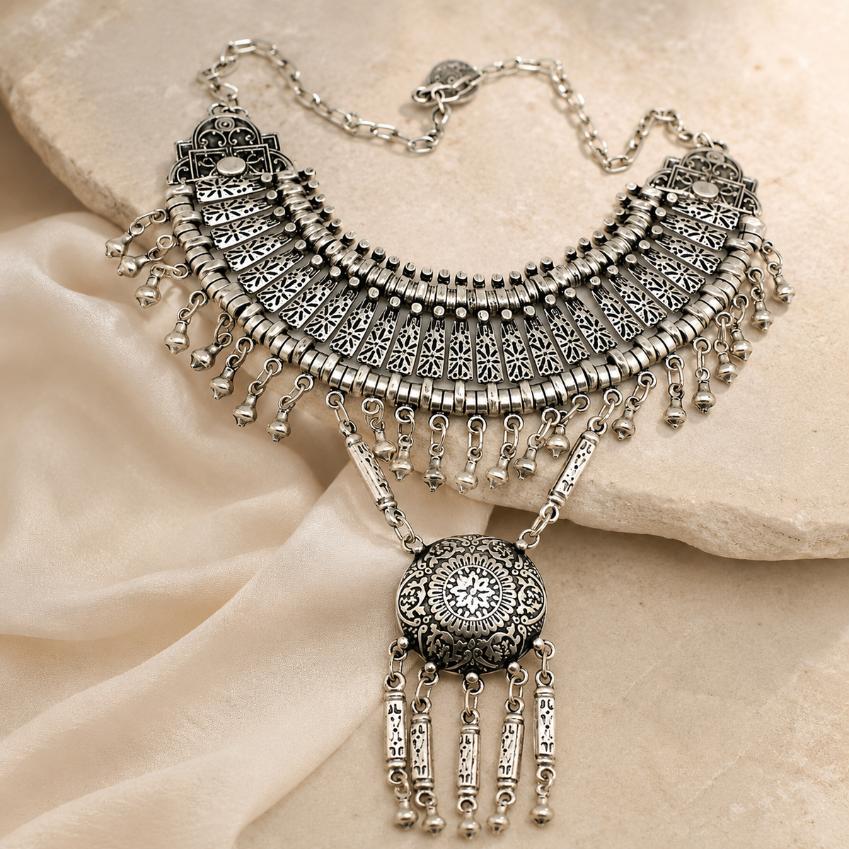 Silver-tone statement necklace with a boho fan silhouette and dangling pendant.
