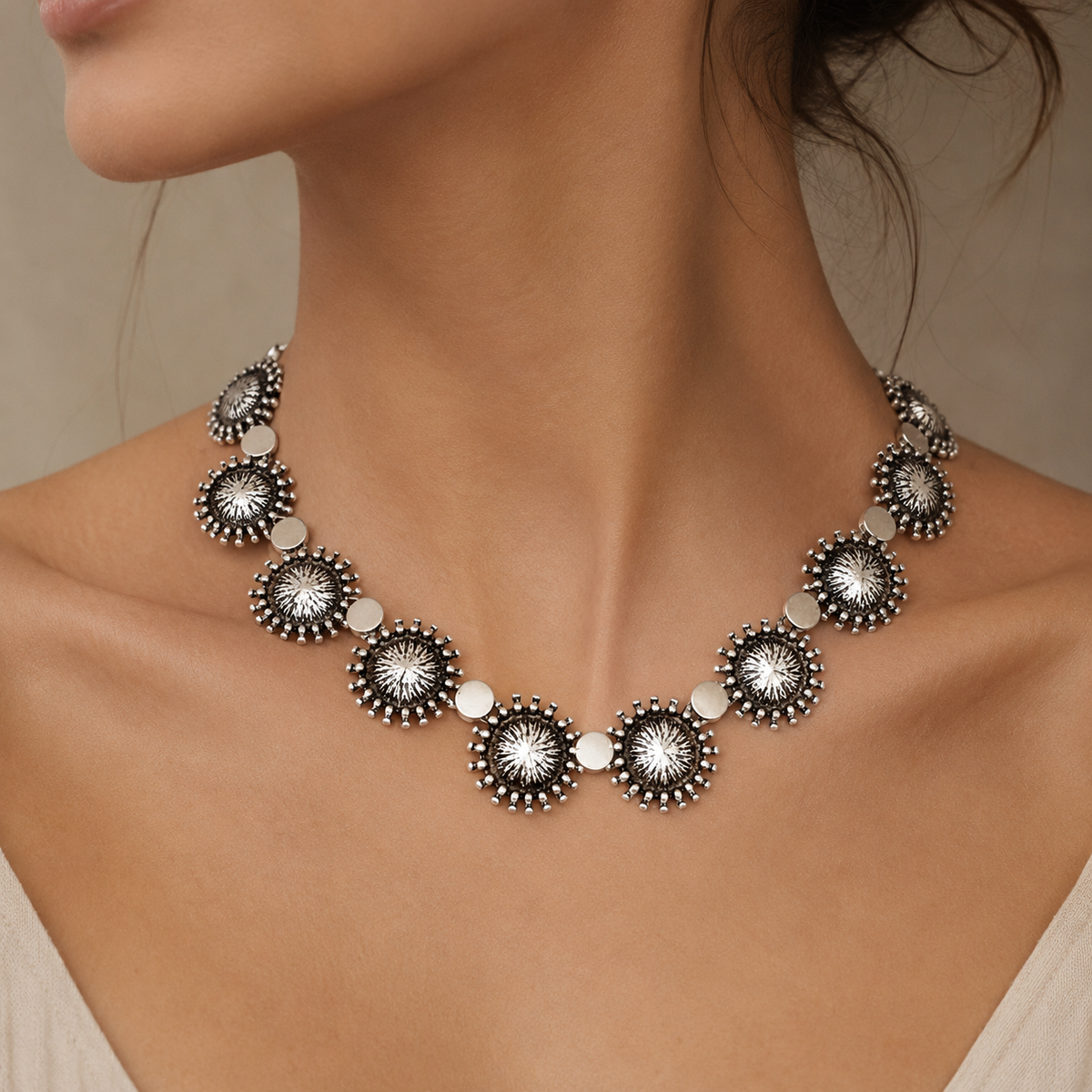 Silver-tone collar necklace with sunburst disc details arranged in a bold circular shape.
