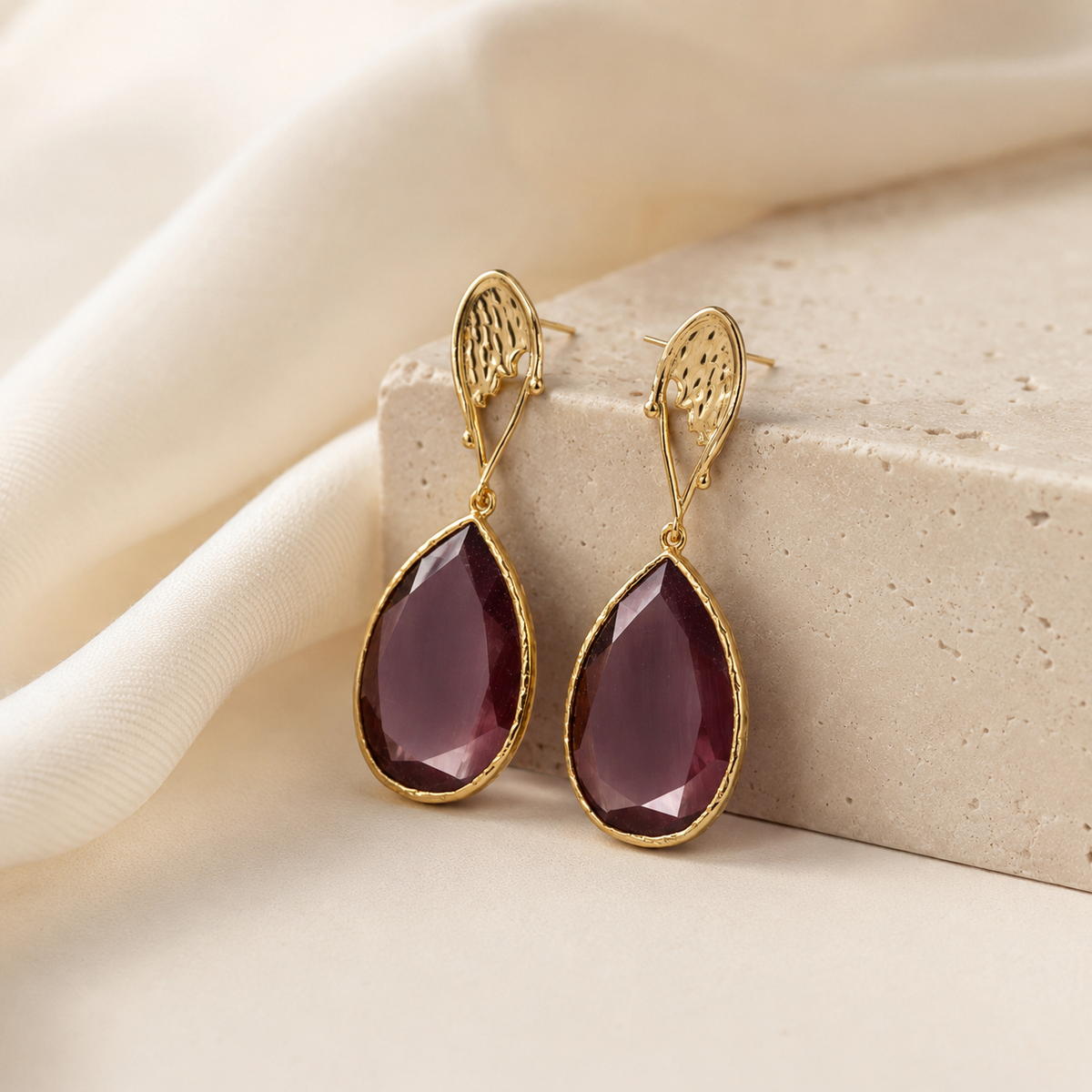 Gold-plated purple drop earring shown on a model's ear.