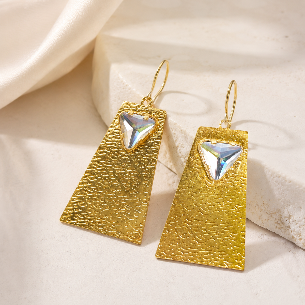 Gold geometric statement earrings with a clear crystal detail.