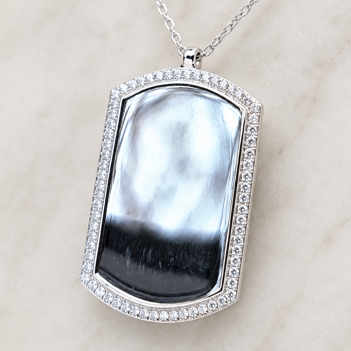 Close view of the dog tag pendant with a CZ frame and glossy center stone.