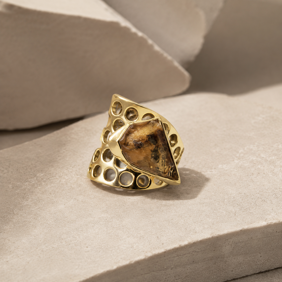 Angled view of a gold-plated honeycomb ring with a rough citrine center stone.
