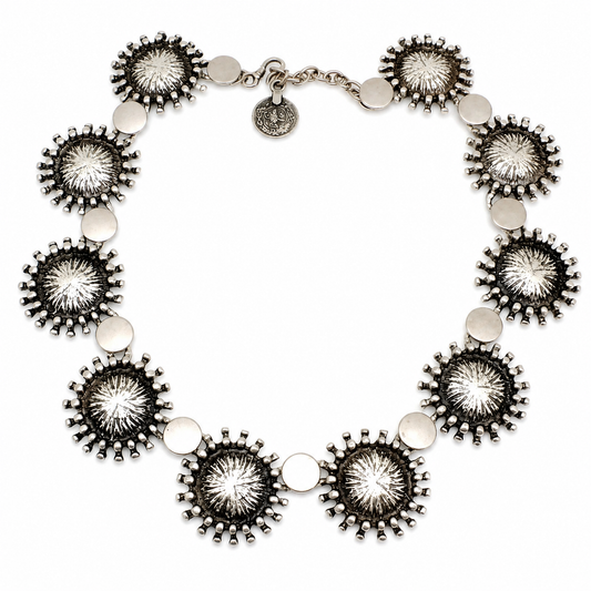 Silver-tone collar necklace with sunburst disc details arranged in a bold circular shape.