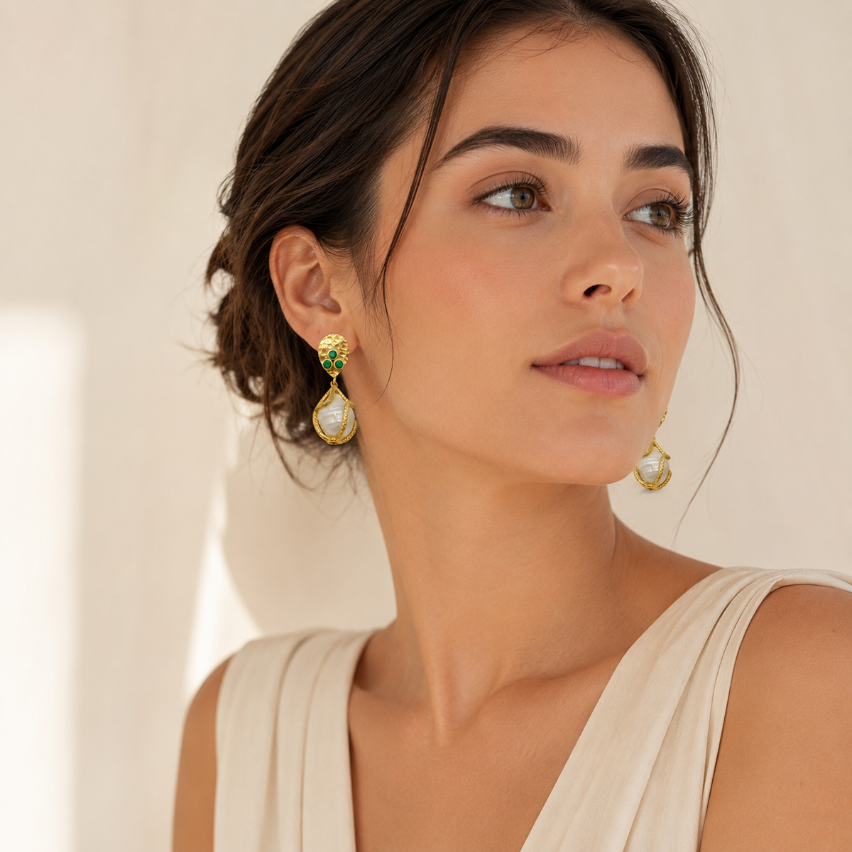 Gold-plated drop earrings with a sculptural cage frame, green CZ accents, and a pearl-like center.