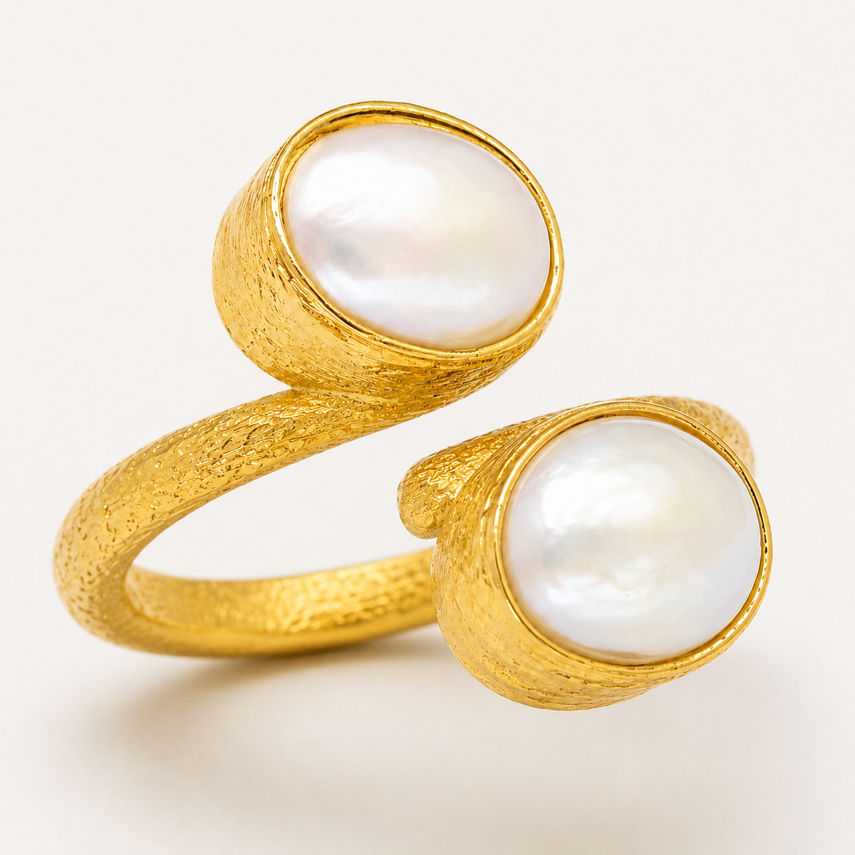 Gold-plated ring with two pearl-like stones worn on the finger.