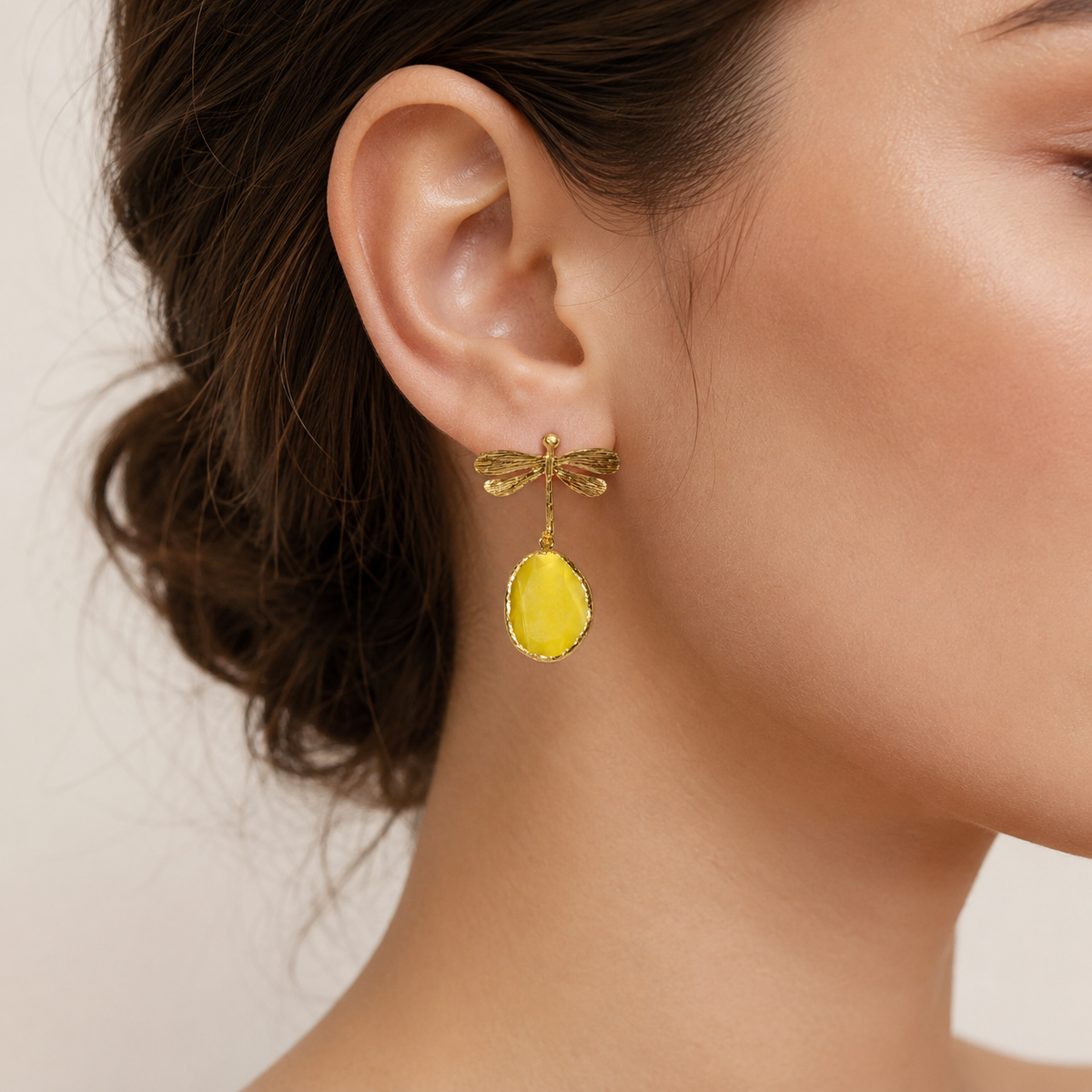 Gold dragonfly drop earrings with textured wings and oval yellow drops.