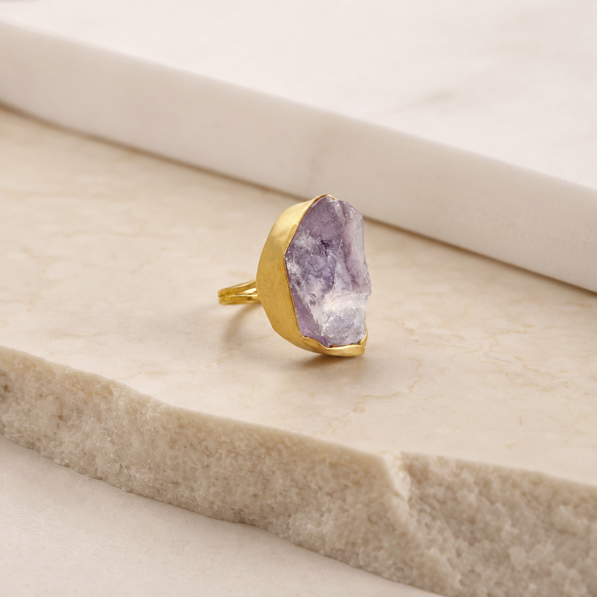 Angle view of a raw amethyst statement ring with gold-plated metal.