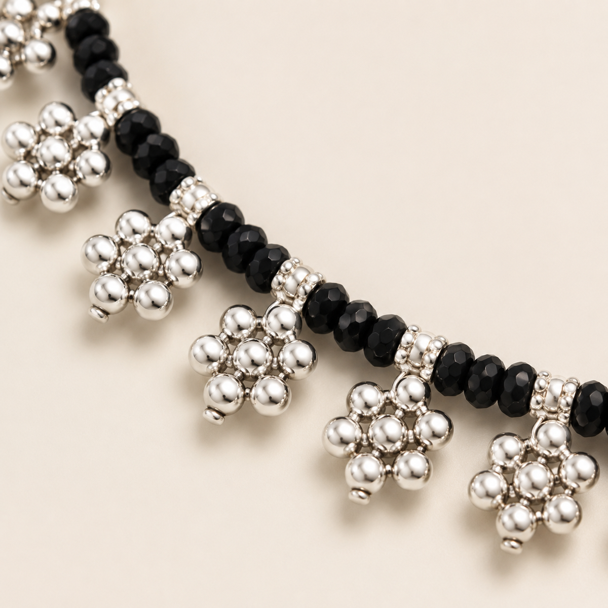 Close view of the black beads and floral fringe details on the necklace.