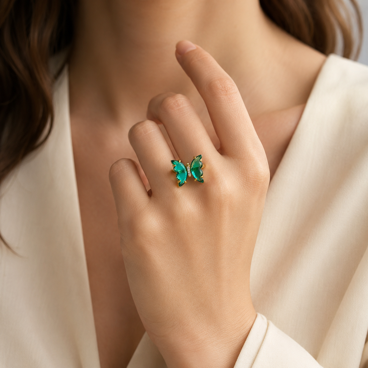 Front view of a butterfly ring with green stones and clear accents.