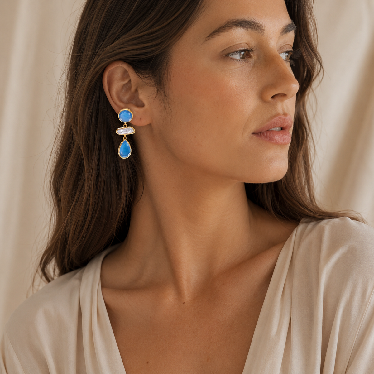 Gold-plated drop earrings with bright blue faceted stones and a pearl-like center.