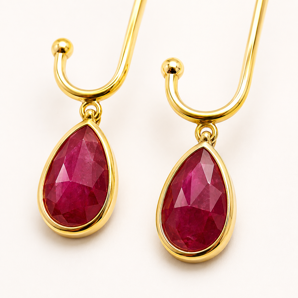 Close view of gold-plated drop earrings with green stone details.