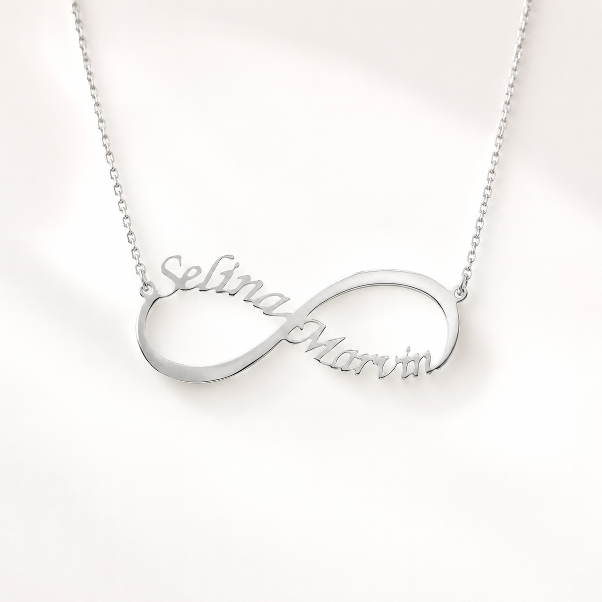 Minimal silver-tone name necklace with a flowing infinity silhouette.
