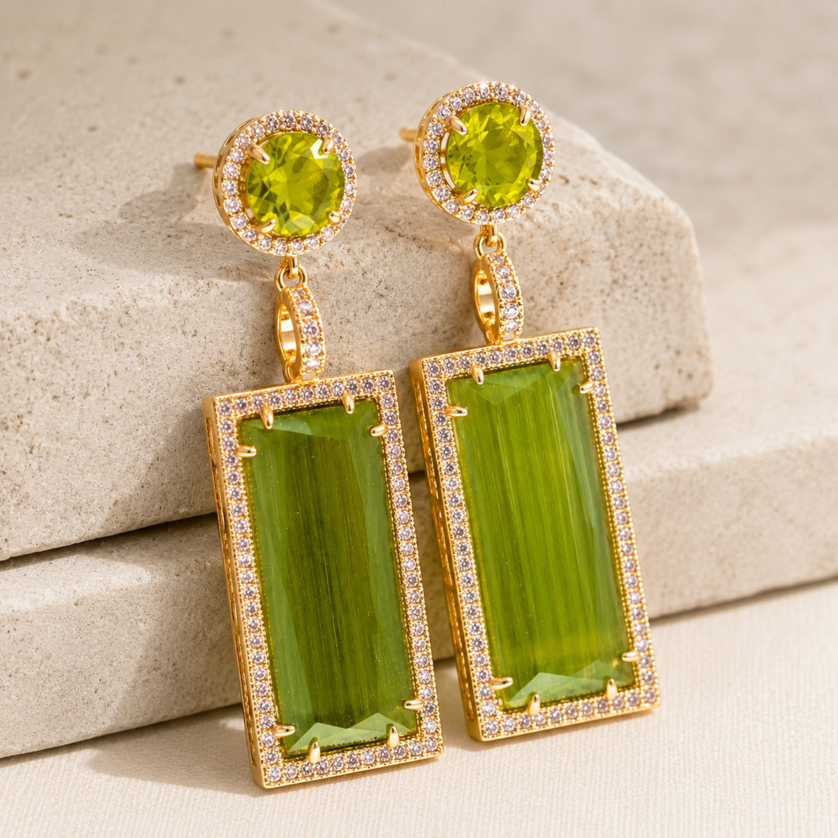Angled view of olive green drop earrings with a gold-plated pavé-style setting.
