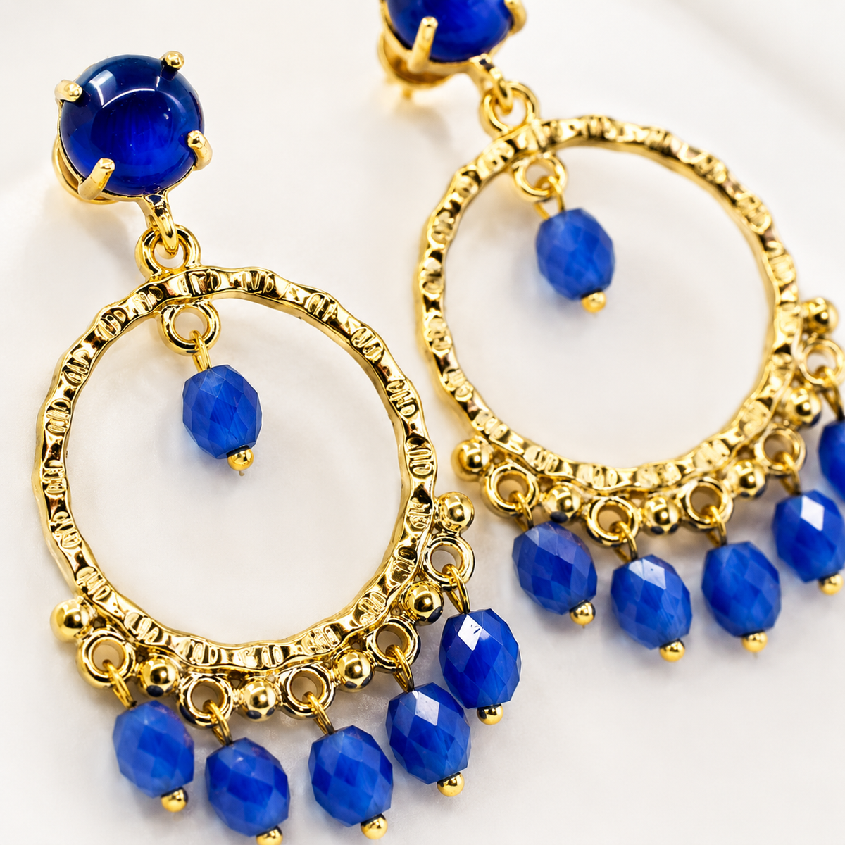 Close view of blue faceted stones and gold-plated details on dangle earrings.