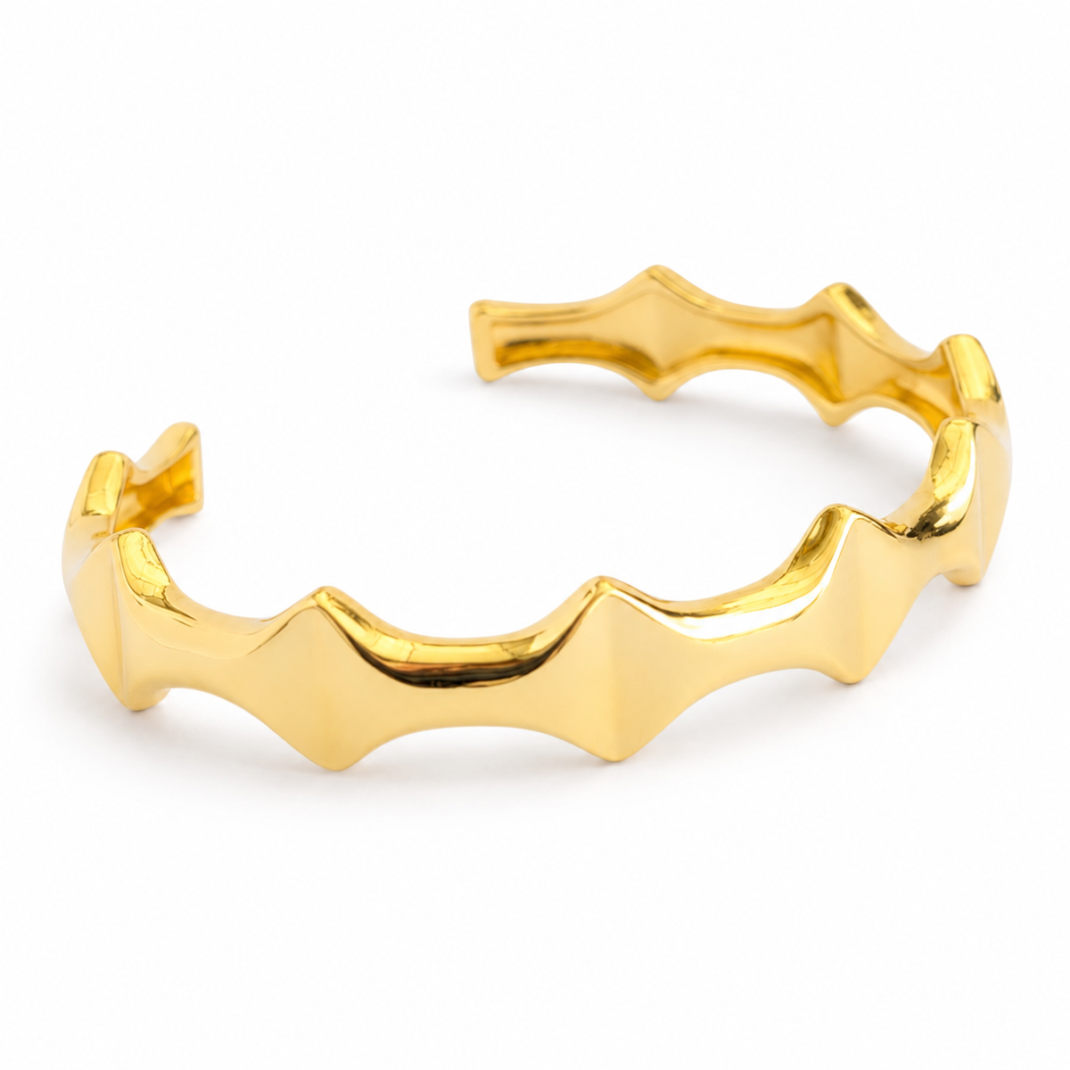 An angled view of a polished gold-tone open cuff bracelet.