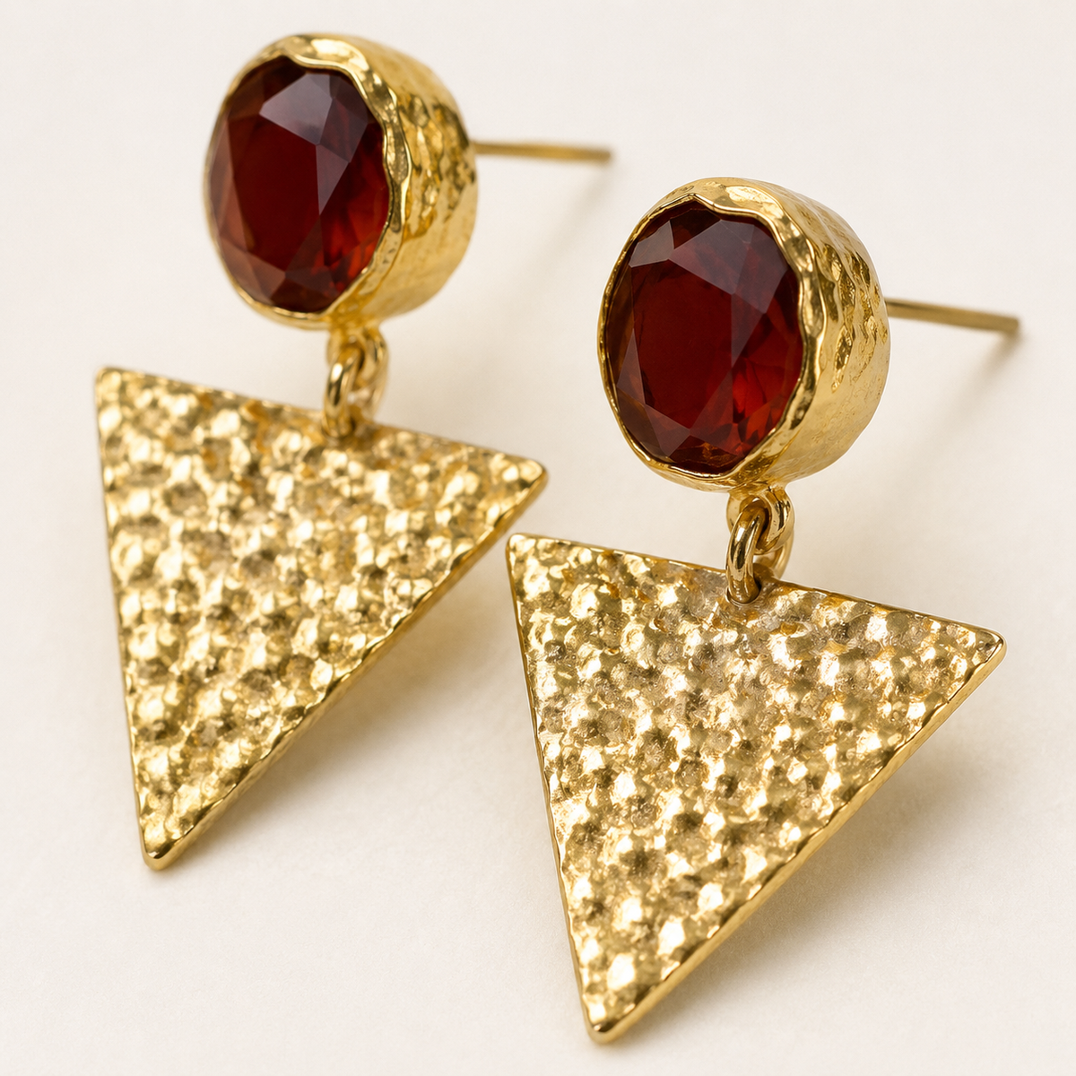 Close view of the faceted orange accent and textured gold-tone triangle earrings.