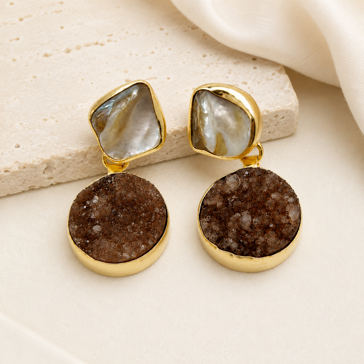 Gold-plated dangle earrings with sculptural black stone-like accents.