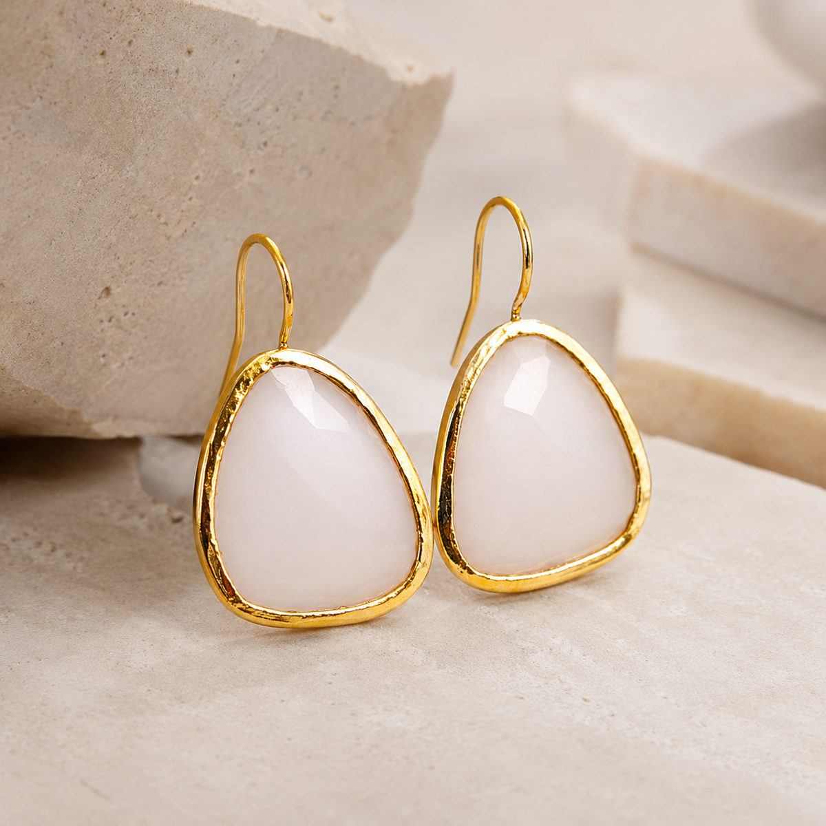 Angle view of white chalcedony drop earrings with a gold-plated frame.
