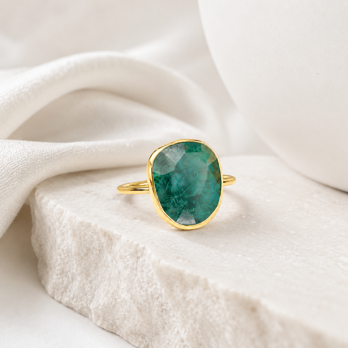 Emerald green oval ring with a polished gold-plated band.