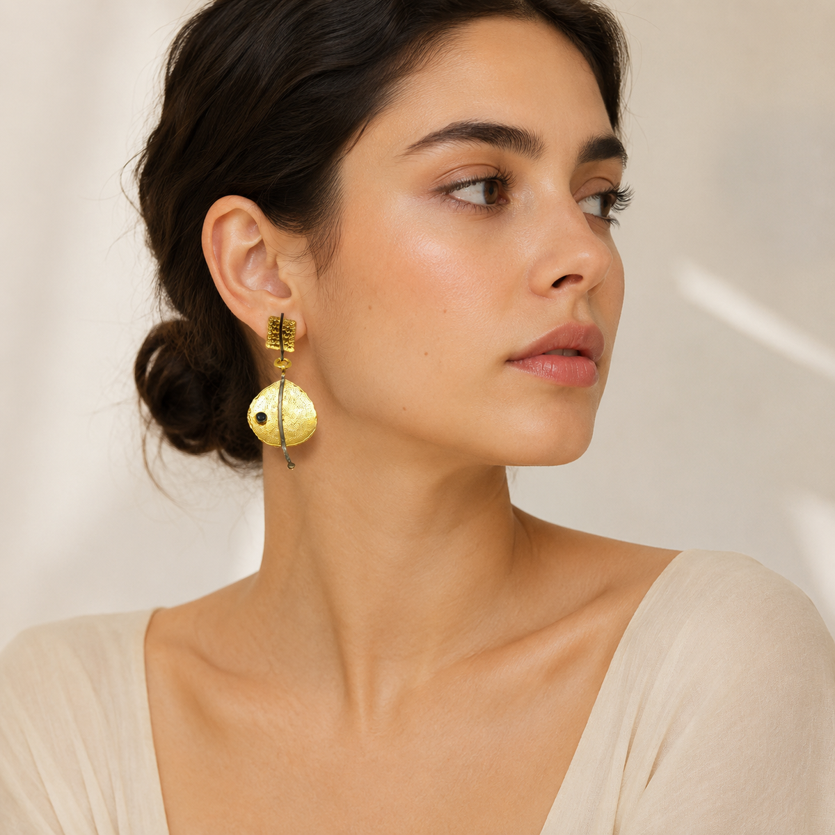 Gold-plated earrings with hammered texture, a black bead, and a long drop shape.