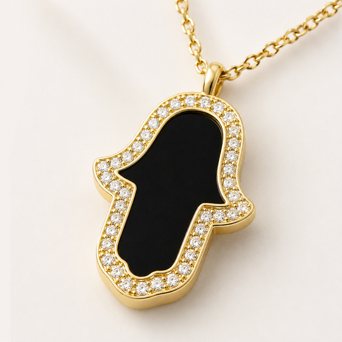 Close view of the black enamel hamsa pendant framed with CZ stones.