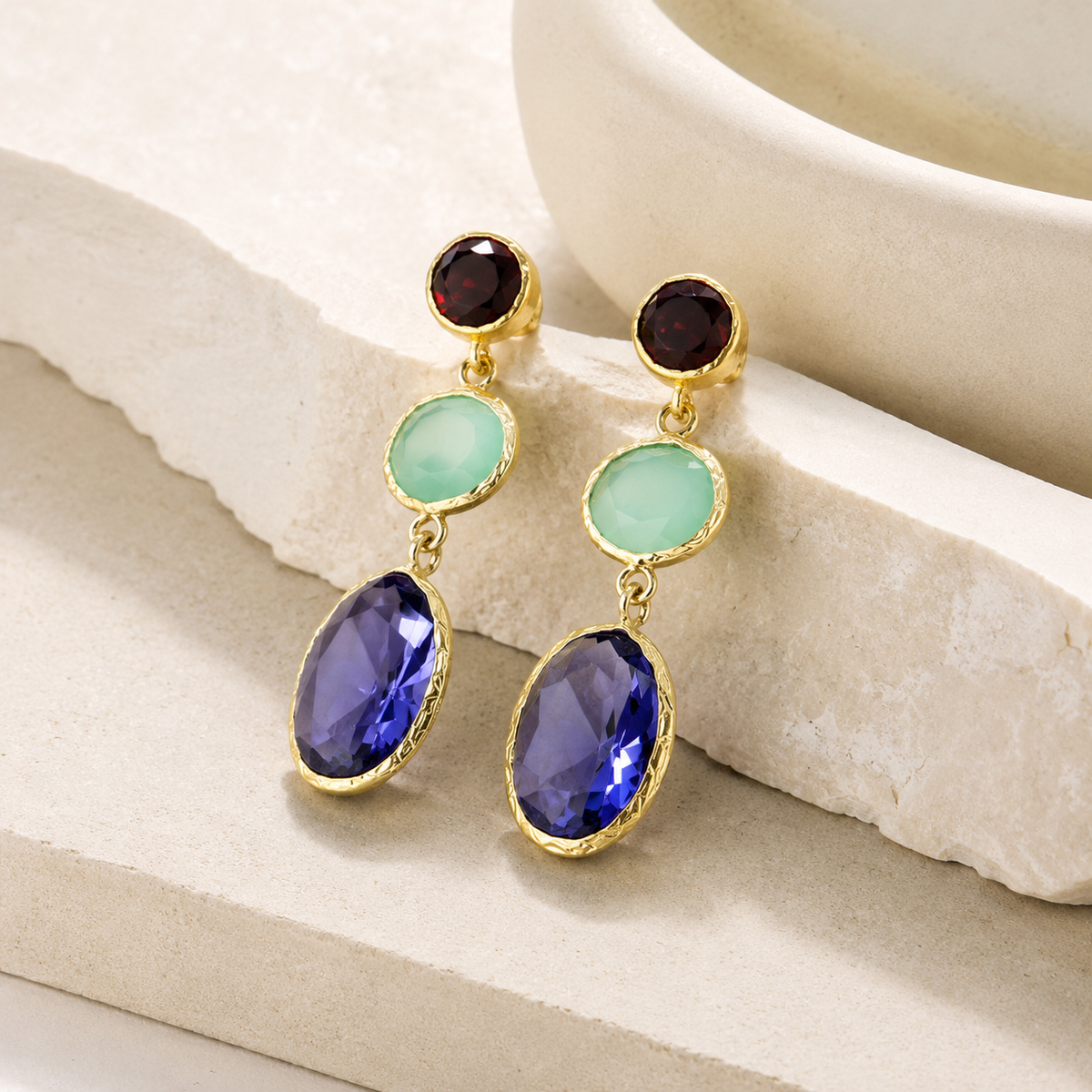 Angled view of gold-plated earrings with three faceted gemstone-style drops.