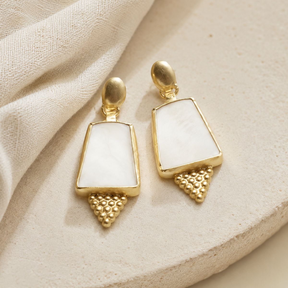 Gold-tone drop earrings with a shield shape and soft pearl-like center panels.