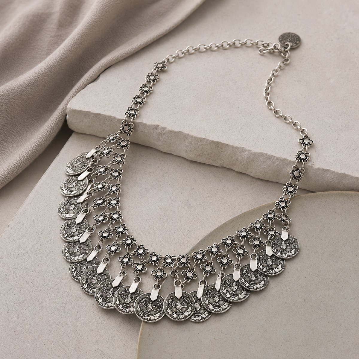 Angled view of the silver-tone floral coin fringe bib necklace.