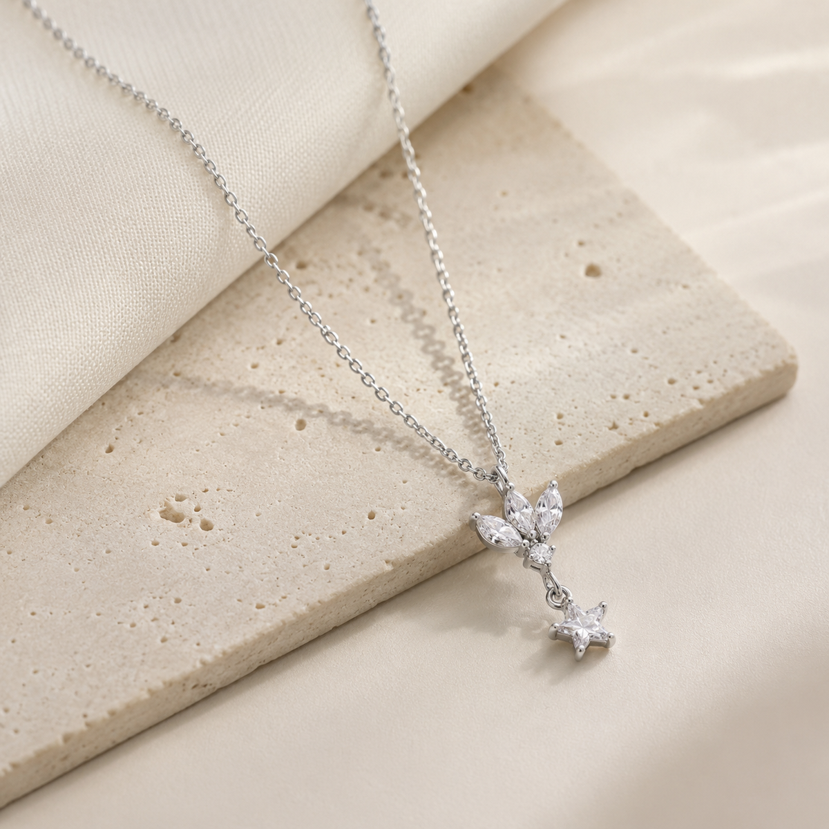 An angled view of the silver-tone pendant necklace with lotus and star details.