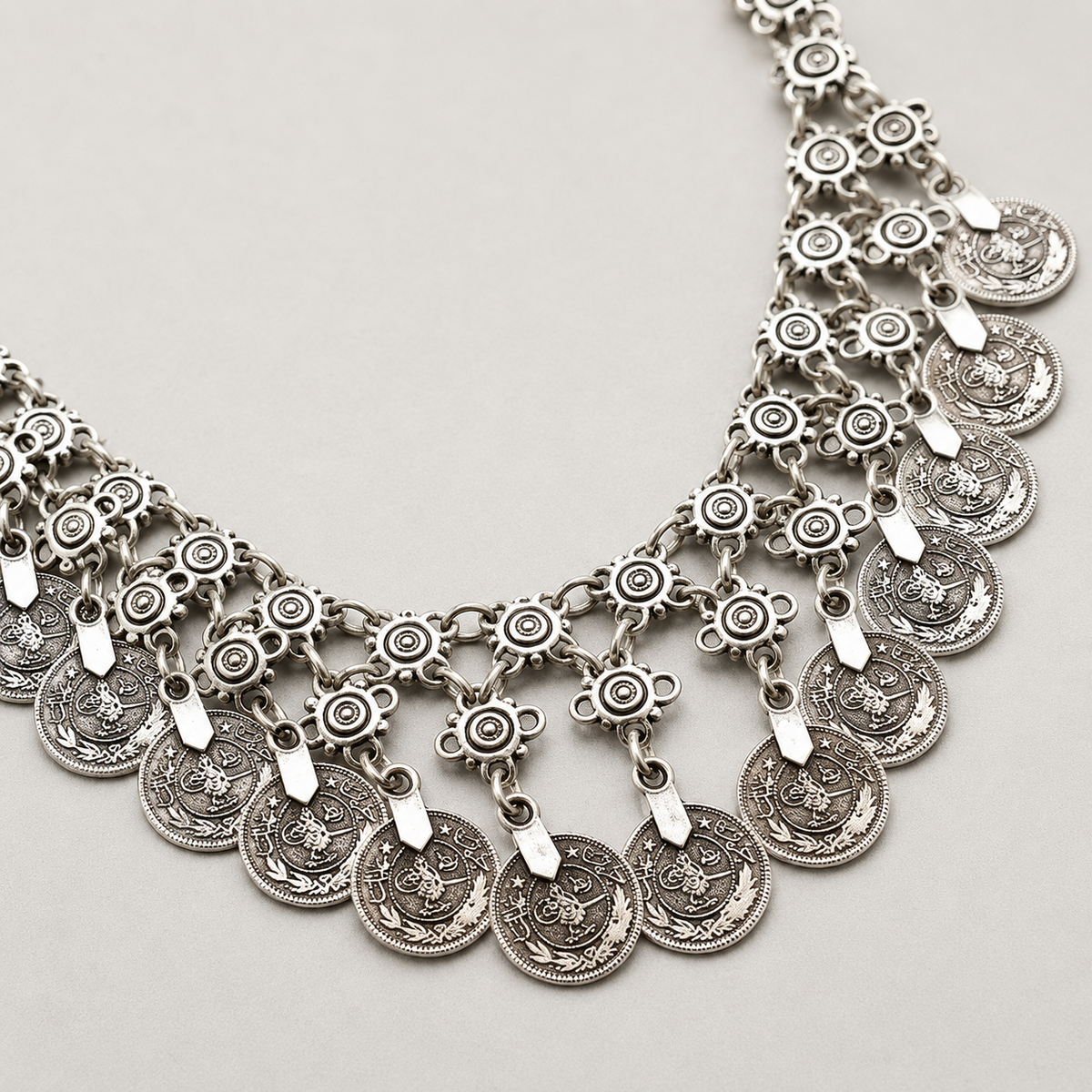 Close view of the necklace's detailed coin and flower links.