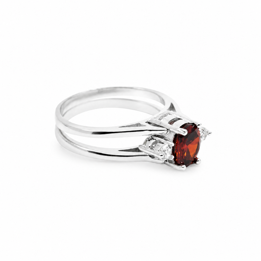 A silver-tone ring with a deep ruby stone and double round band design.