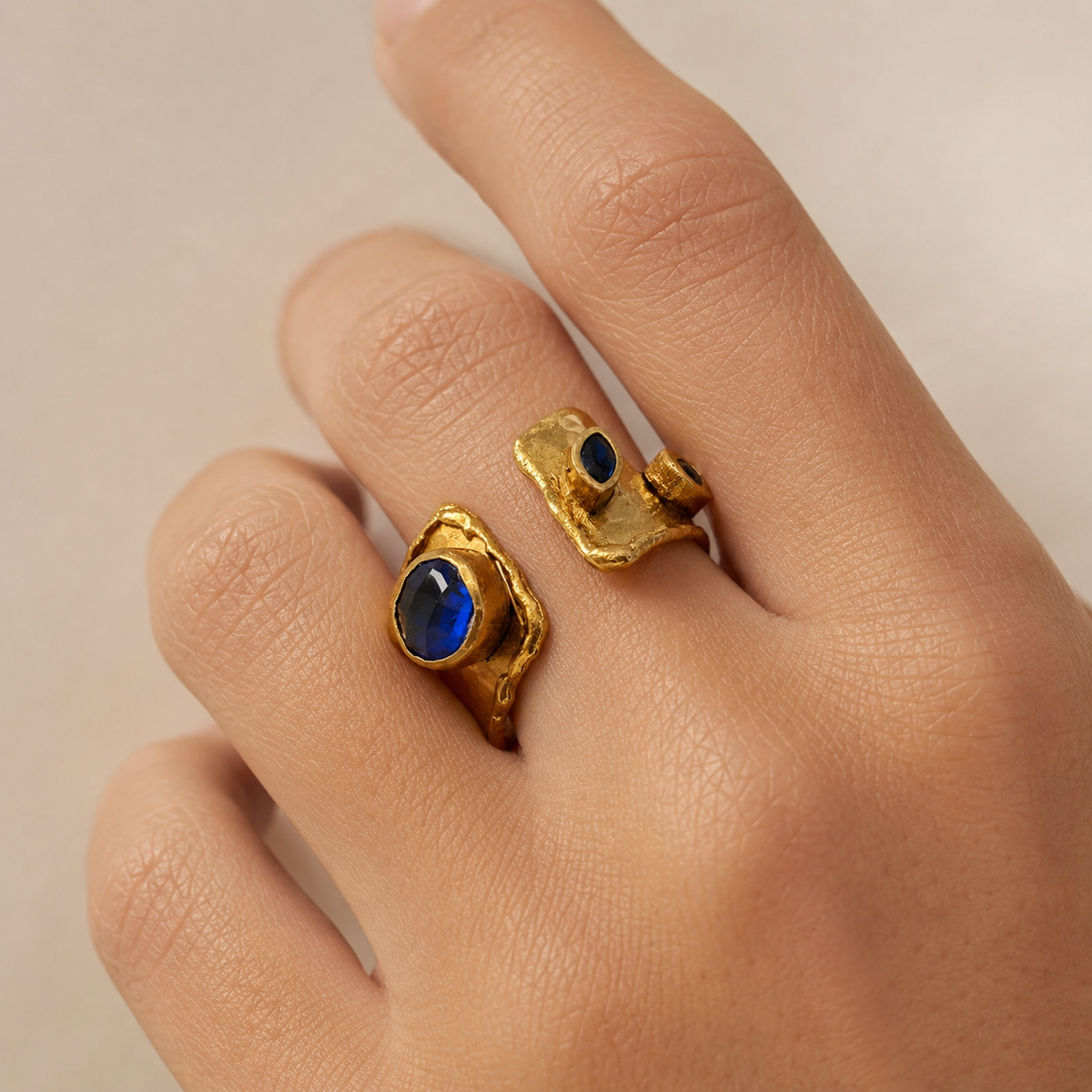 Gold-plated open cuff ring with sapphire blue stone accents.