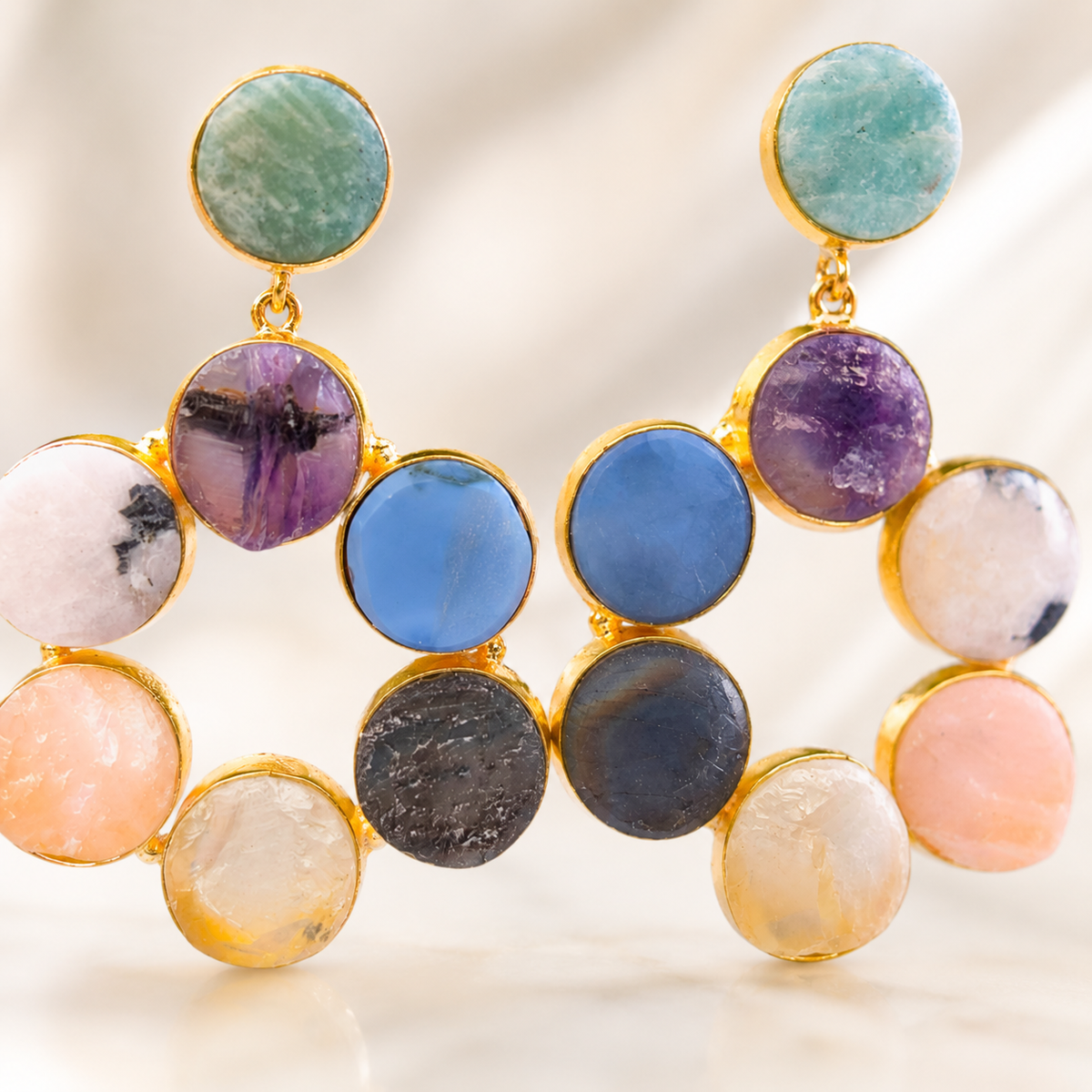 Close view of gold-tone statement earrings with colorful round gemstone-style stones.
