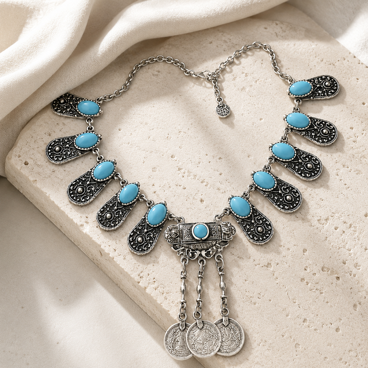 Layered silver-toned pendant necklace with engraved panels and coin charms.