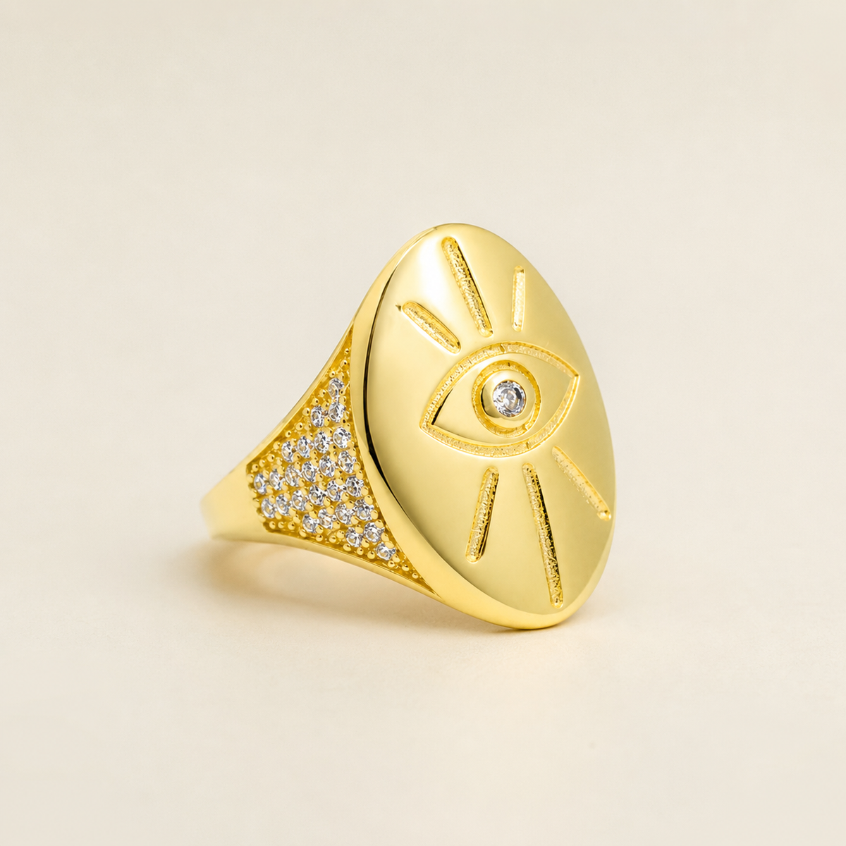Angled view of a polished gold-tone evil eye signet ring.