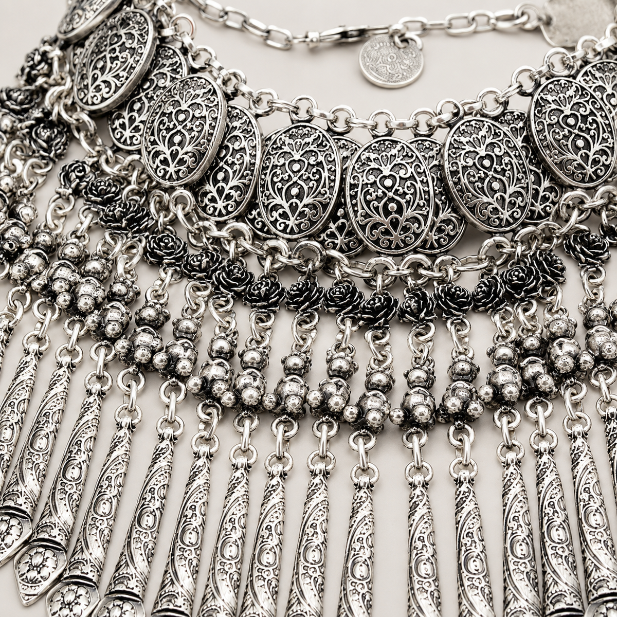 Close view of the silver-tone coin and fringe details on the necklace.