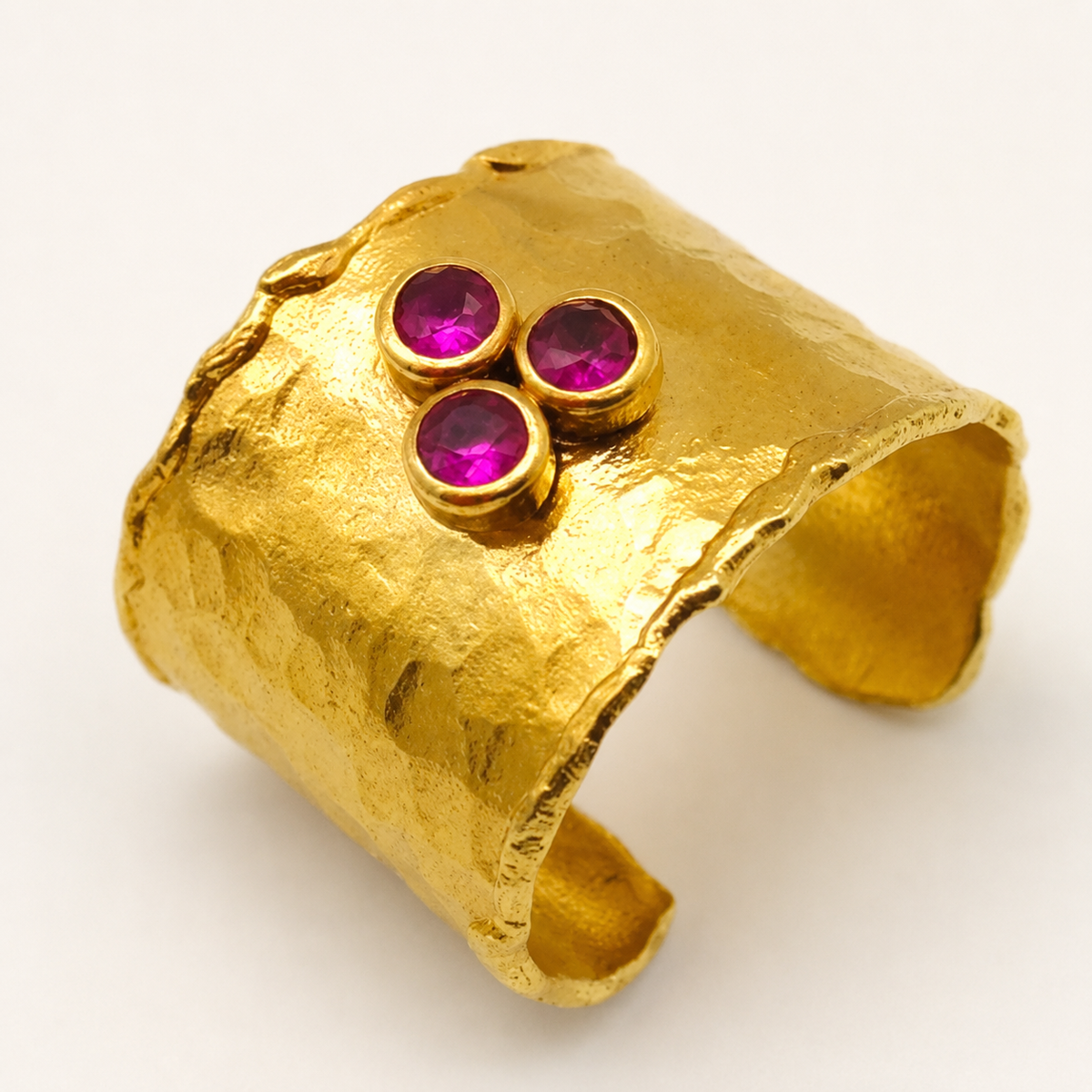 Close view of the three ruby pink stones set in the gold cuff ring.