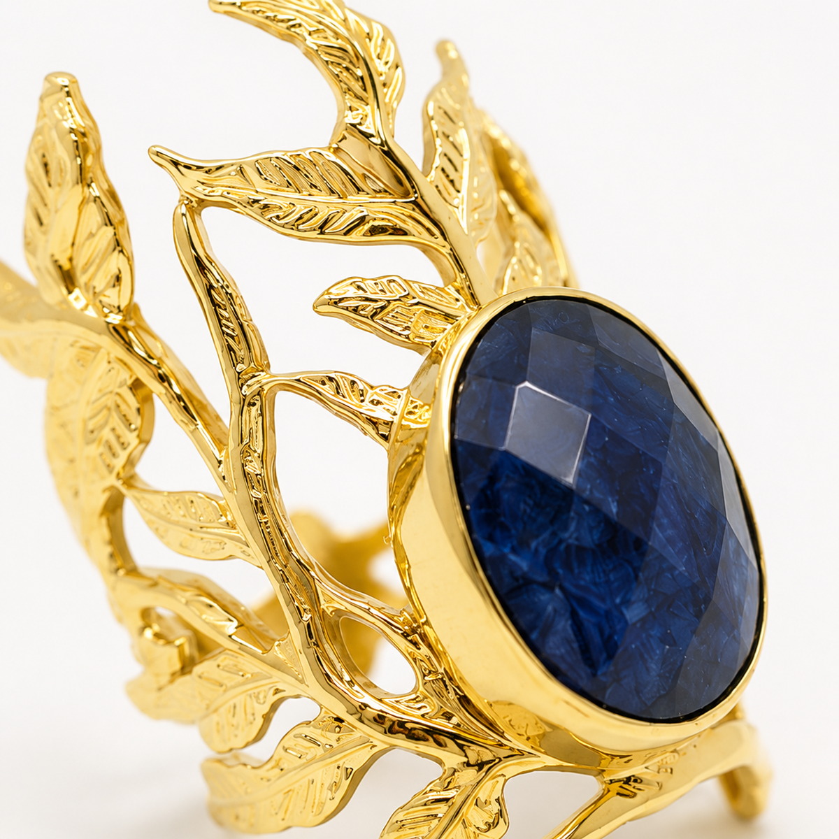 Gold ring with an oval navy blue stone and open leaf design.