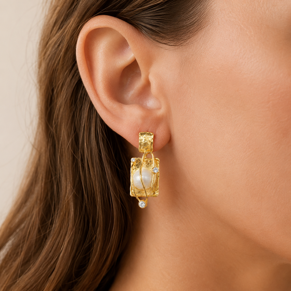 Pair of gold-plated pearl drop earrings shown front on.