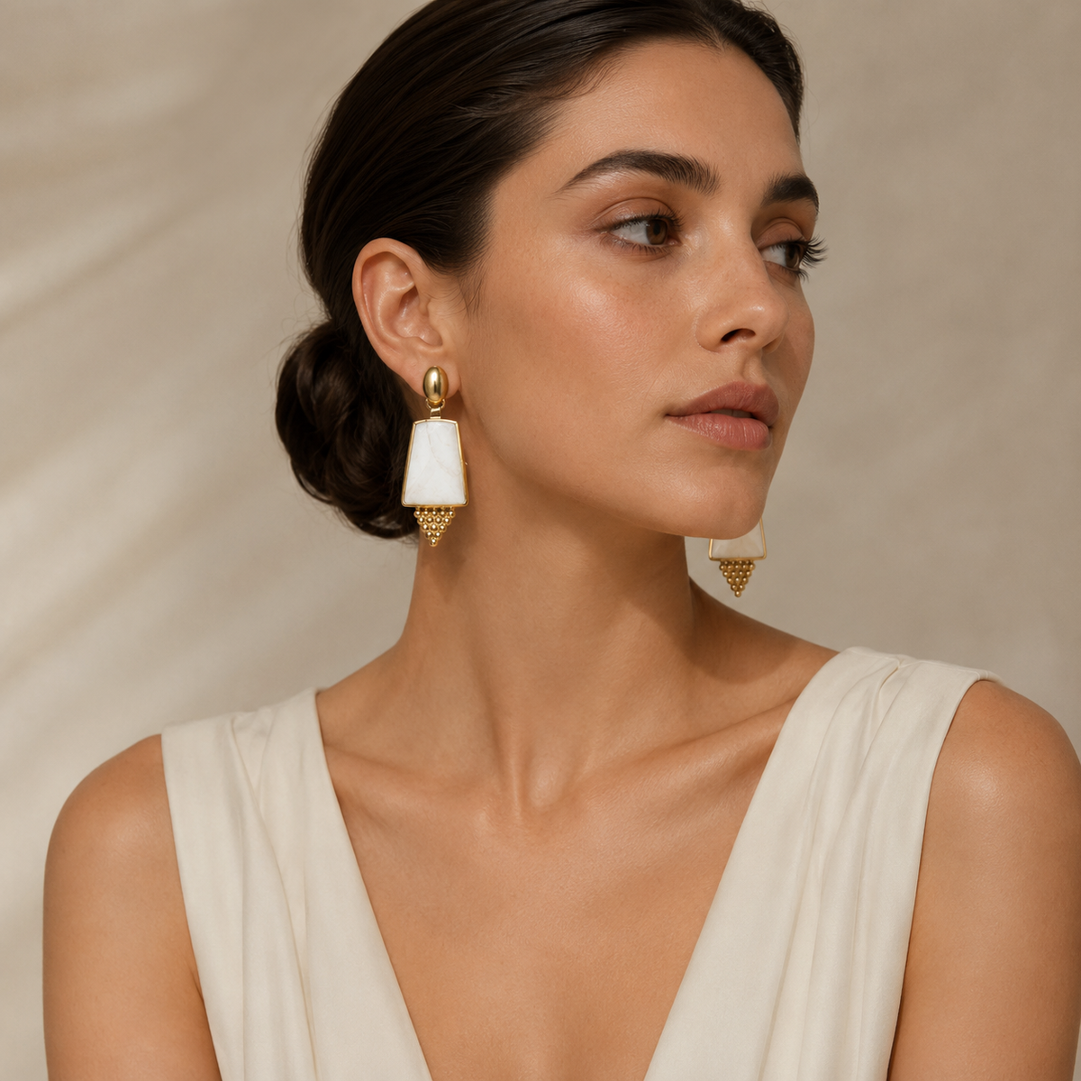 Statement drop earrings with gold-plated framing and pearl-like shield details.