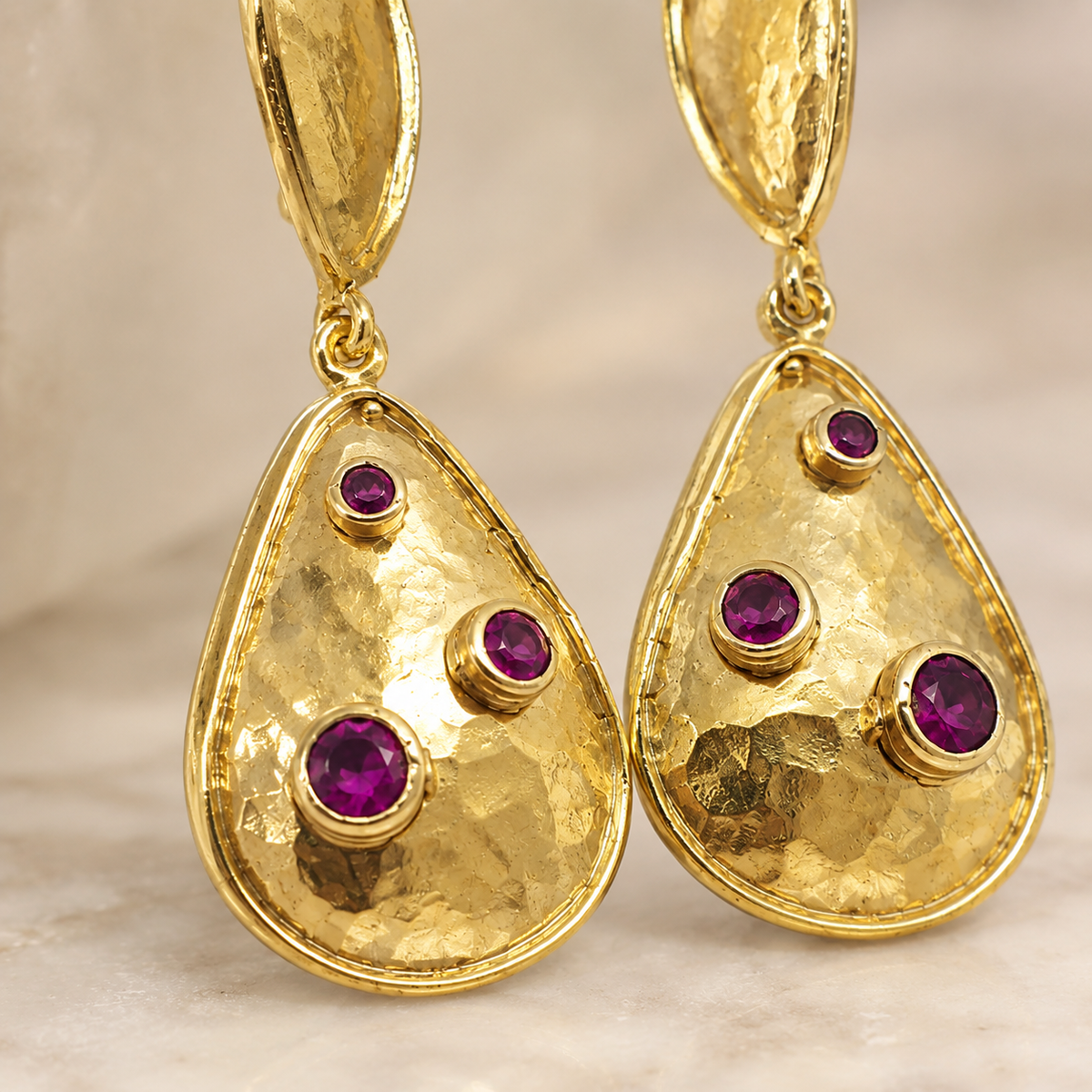 Close-up of gold-plated teardrop earrings with clear crystal details.