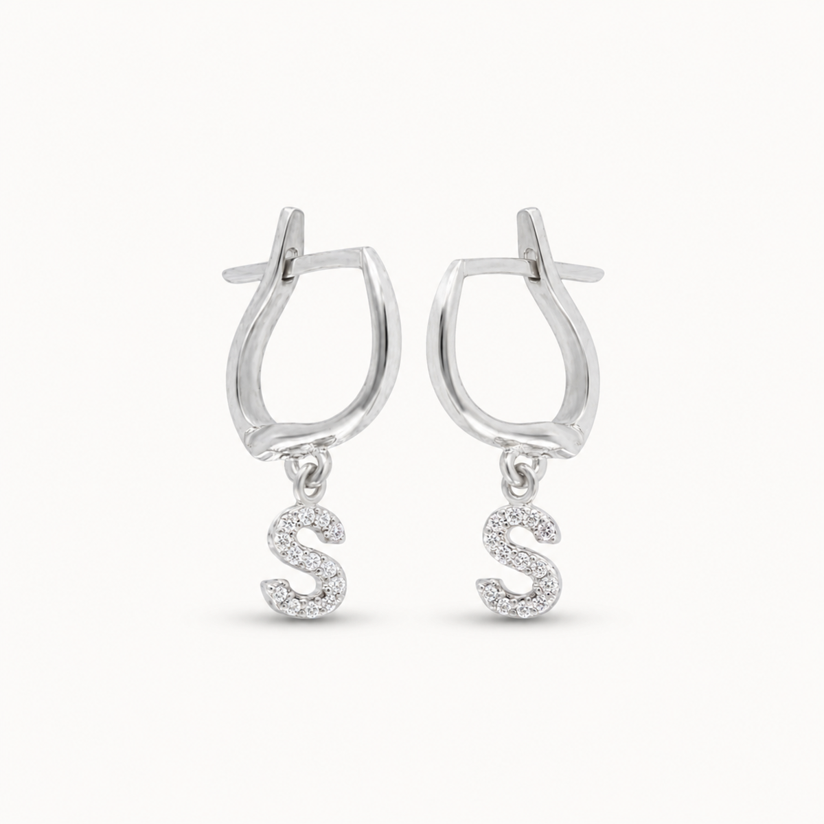 Silver-tone huggie earrings with a dangling CZ initial charm.