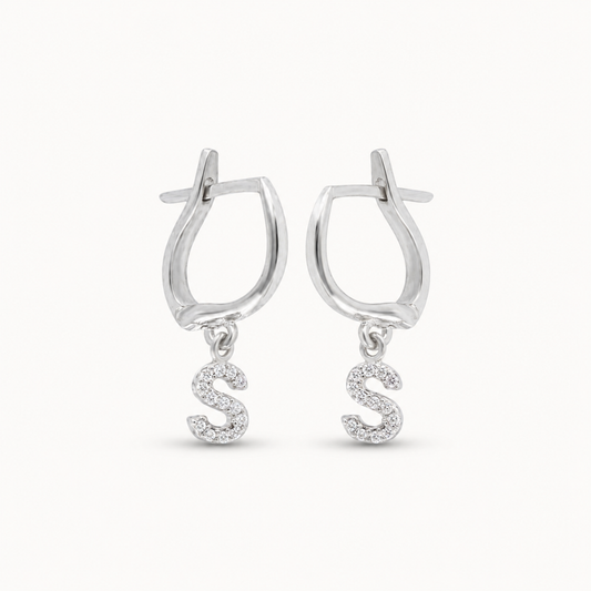 Silver-tone huggie earrings with a dangling CZ initial charm.