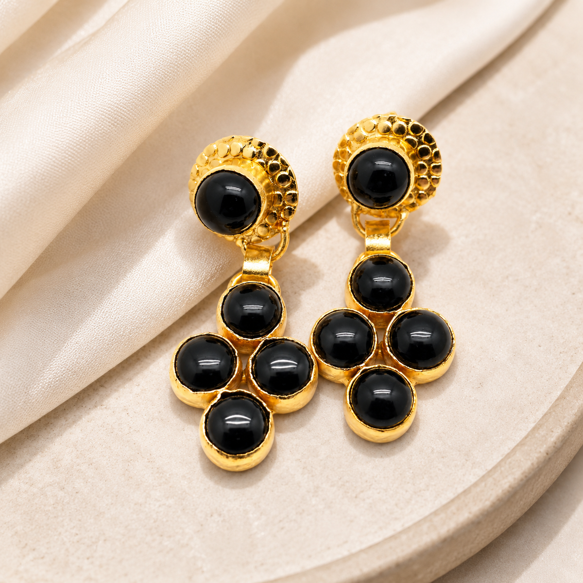 Gold-plated black onyx dangle earrings with a bold drop shape.