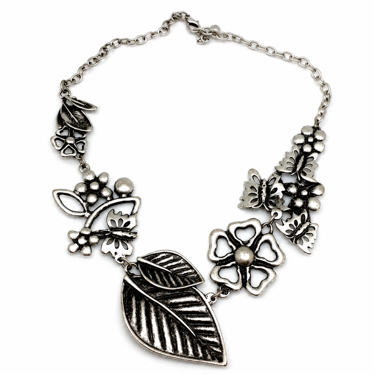Silver-tone statement necklace with floral and leaf charms on a white background.