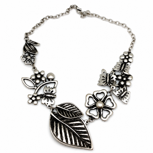 Silver-tone statement necklace with floral and leaf charms on a white background.